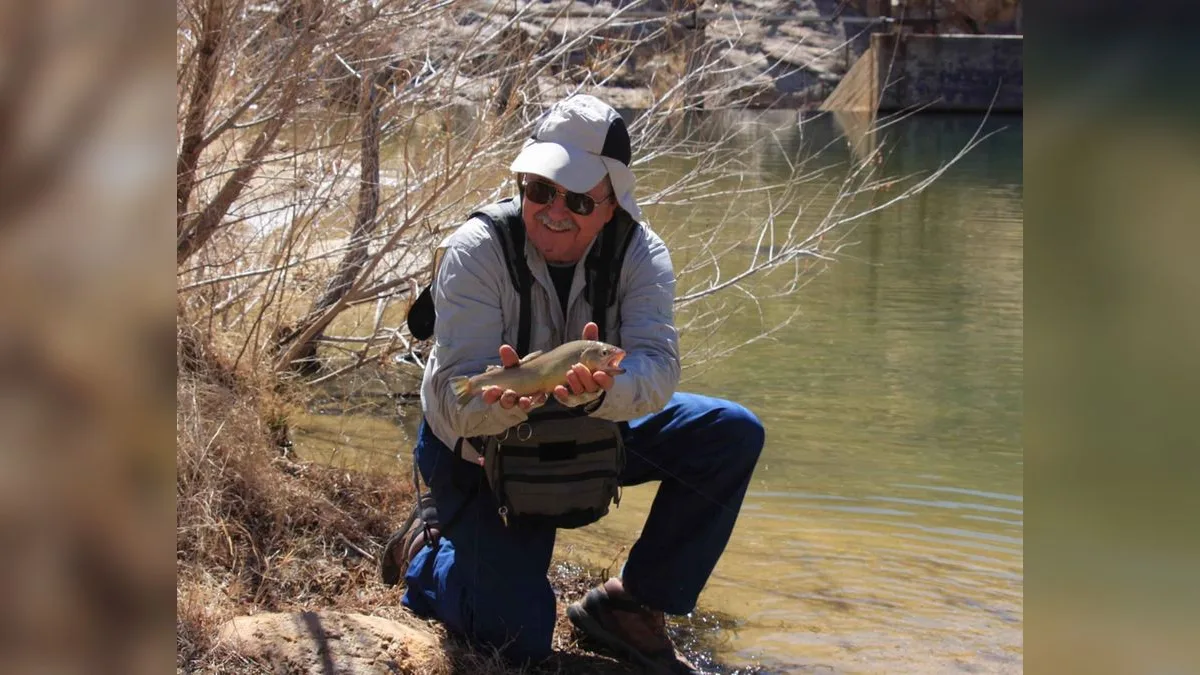 Angler hält eine gefangene Forelle kurz über dem Wasser, bevor er sie zurücksetzt