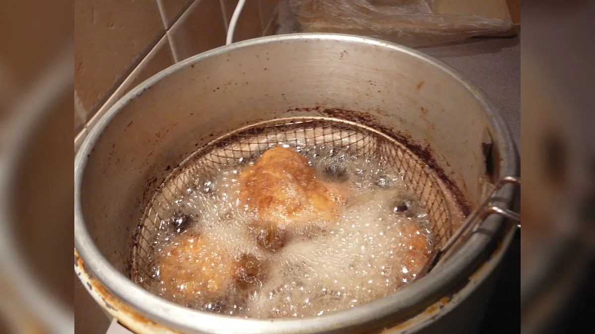Panierte Karpfenstücke beim Frittieren im Fettbad