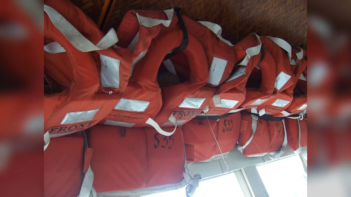 Reihe orangefarbener Rettungswesten in einem Boot